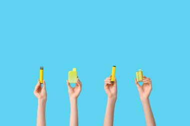 Mavi arka planda elektronik sigara tutan bir sürü el var.