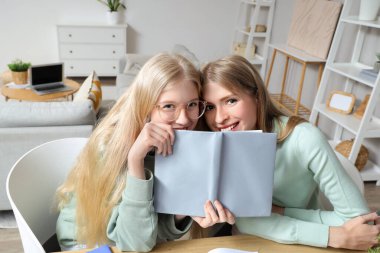 Güzel, genç ve mutlu kız kardeşler evde ödev yapıyor.