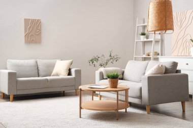 Gri kanepeleri ve masası olan aydınlık oturma odasının içinde.