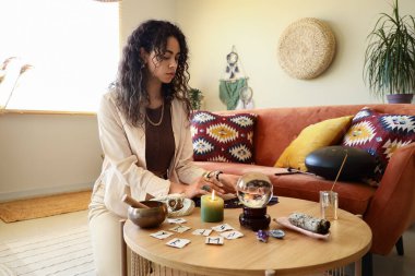 Genç Afro-Amerikalı cadı evde tarot kartları okuyor.