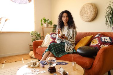 Genç Afro-Amerikan cadı Tibet kâsesi ile evdeki kanepede oturuyor.