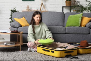Evinde yerde yastığı valize koyan genç bir kadın. Seyahat kavramı