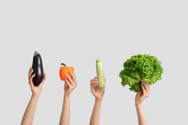 Female hands holding fresh vegetables on white background