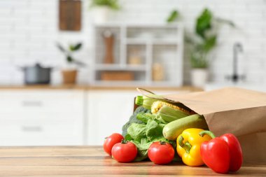 Ahşap mutfak tezgahında farklı taze sebzelerle alışveriş torbası.