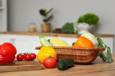 Tahta mutfak tezgahında farklı taze sebzelerle dolu bir sepet.