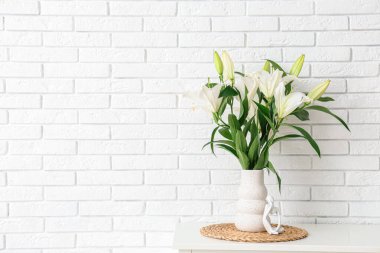 Beyaz tuğla duvarın yanındaki çekmecelerde çiçekli vazo, yakın plan.