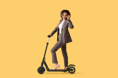 Turuncu arka planda tekmeleyen gözlüklü olgun bir iş kadını.