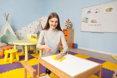 Anaokulunda kadın kreş öğretmeninin dezenfekte masası