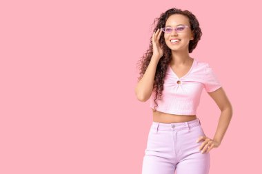 Pembe arka planda güneş gözlüklü güzel bir Afro-Amerikalı kadın.