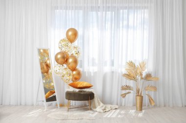 Modern oturma odasının penceresinin yanında yer aynası, puf ve hava balonları.