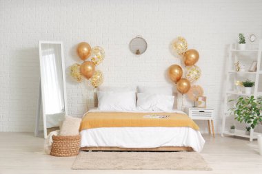 Altın hava balonları ve rahat yatak odası beyaz tuğla duvarın yanında