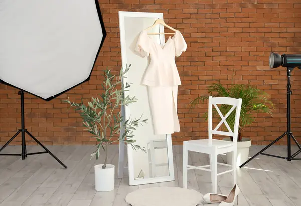 Profesyonel ekipman, sandalye, ayna ve elbise ile şık bir fotoğraf stüdyosu.