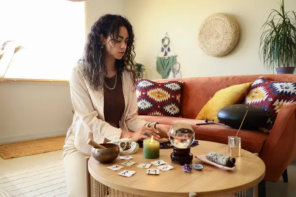 Genç Afro-Amerikalı cadı evde tarot kartları okuyor.