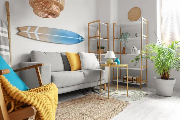 Rahat kanepesi, sehpası, raf ünitesi ve sörf tahtasıyla oturma odasının içi aydınlık.