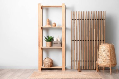 Odanın içi ahşap perdeli, hasır lambalı ve beyaz duvarın yanındaki raf üniteli.