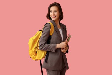 Pembe arka planda not defterleri ve sırt çantası olan güzel bir kız öğrenci.