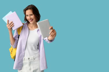 Sırt çantası ve mavi arka plan kitapları olan güzel bir kız öğrenci.