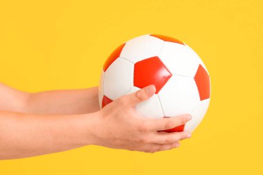 Sarı arka planda futbol topu olan genç çocuk, yakın plan.