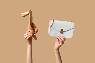 Bej arka planda kadın eli ve topuklu ayakkabı.