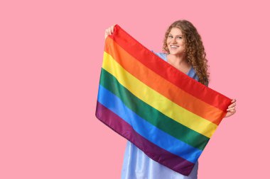 Pembe arka planda LGBT bayrağı olan güzel genç bir kadın.