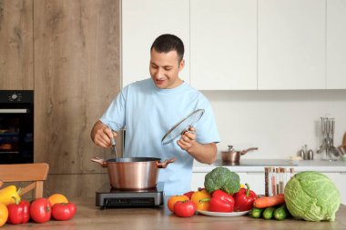 Genç adam mutfakta çorba pişiriyor.