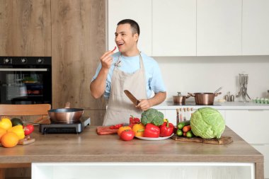 Genç adam mutfakta biber kesiyor.