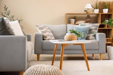 Gri kanepeleri ve masası olan oturma odasının içinde.