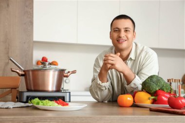 Mutfaktaki masada taze sebzeli genç adam.