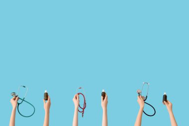 Mavi arka planda burun damlası ve steteskoplu eller.