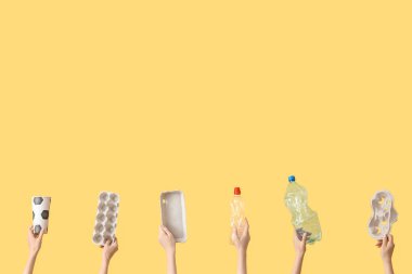 Sarı arka planda çöpleri olan kadın eller. Geri dönüşüm kavramı