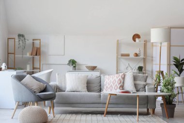 Gri koltuklu, koltuklu ve yumuşak yastıklı bir oturma odası.