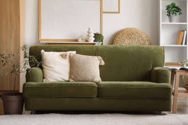 Modern oturma odasının içindeki yumuşak yastıklı yeşil kanepe.