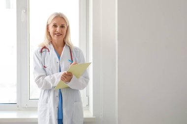 Hastanenin penceresinin yanındaki panoya yazı yazan kadın doktor.