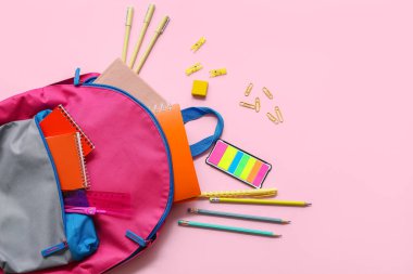 Okul çantasında pembe arka planda farklı kırtasiye malzemeleri var.