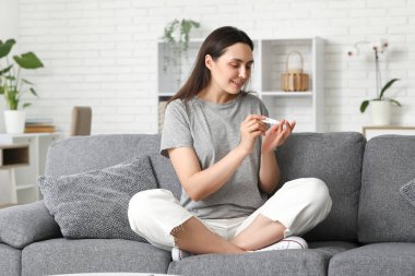 Şeker hastası genç bir kadın evdeki kanepede tükenmez kalem kullanıyor.