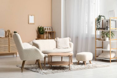 Beyaz kanepesi, koltuğu ve ahşap masası olan şık bir oturma odası.