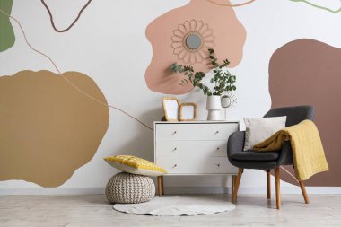 Koltuk, fotoğraf çerçeveleri ve okaliptüs dallarıyla dolu vazolar güzel odadaki çekmecelerin üzerinde.