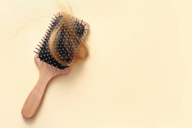 Bej arka planda saç teli olan fırça. Saç dökülme problemi