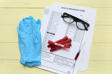 HIV testi tüpleri, laboratuvar raporu formu ve sarı ahşap arka planda şırınga.