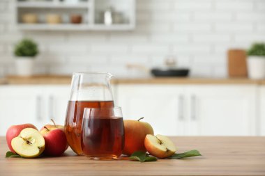 Mutfaktaki ahşap masada bir bardak taze elma suyu.