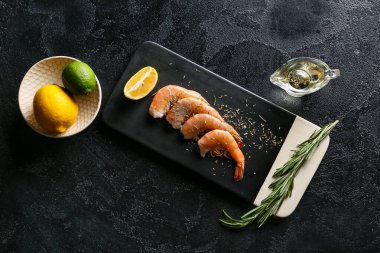 Lezzetli haşlanmış karides, biberiye ve limonlu siyah arka plan.