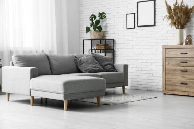 Oturma odasında rahat bir kanepe, saksı ve raf ünitesi var.