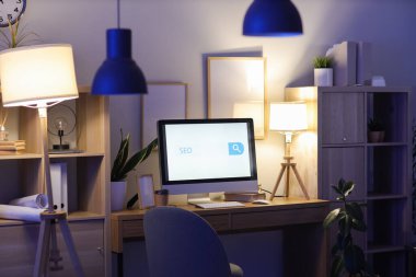 SEO kısaltmalı bilgisayar ekranı ve karanlık ofiste arama çubuğu
