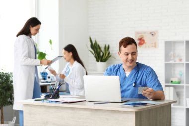 Klinikteki masada ilaçlı erkek doktor.