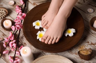 Güzellik salonunda kaplıca pedikür yaptıran genç bir kadın.