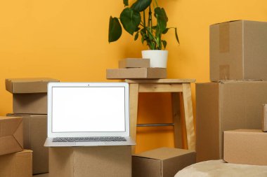 Turuncu duvarın yanındaki kutuları taşıyan boş dizüstü bilgisayar.