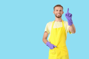 Lastik eldivenli erkek hademe mavi arka plandaki bir şeyi işaret ediyor.