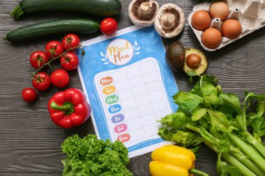 Ahşap arka planda sağlıklı ürünler ve haftalık yemek planı. Diyet kavramı