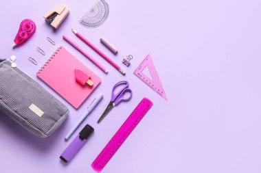 Leylak arka planında farklı kırtasiye malzemesi olan gri kalem kutusu. Üst görünüm