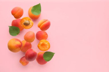 Pembe arka planda yaprakları olan uçan kayısılar.